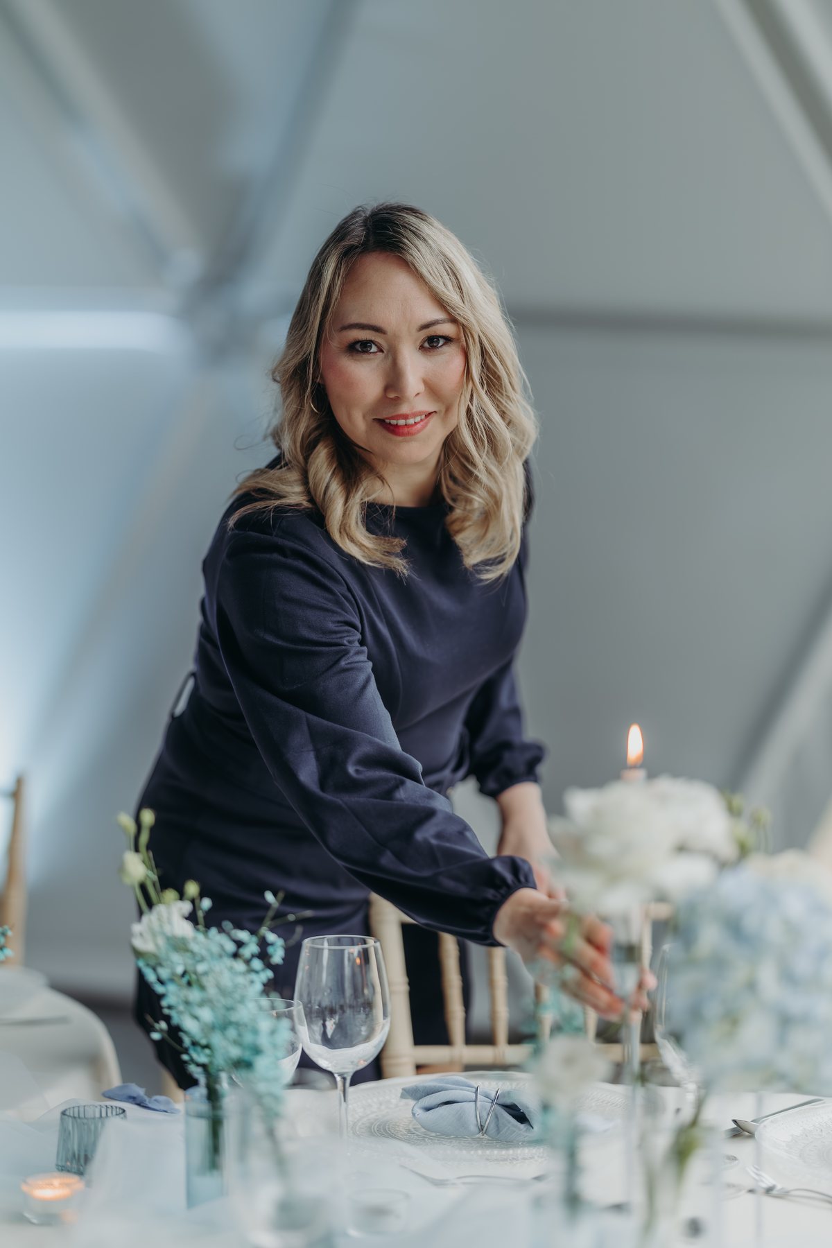 Anastasia Kraft richtet ein Tablesetting mit Blumen und Kerzen an